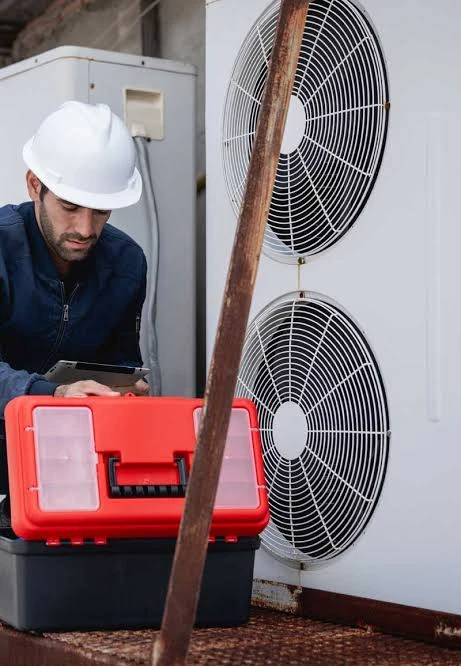 Technician checking outdoor HVAC equipment with a tablet